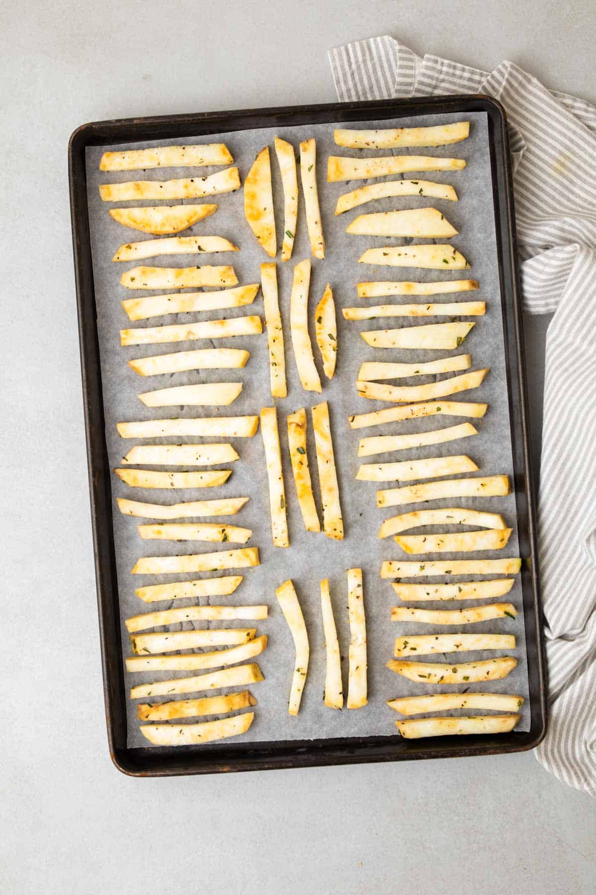 Frites en une seule couche sur une plaque à pâtisserie, prêtes à aller au four, vues du dessus