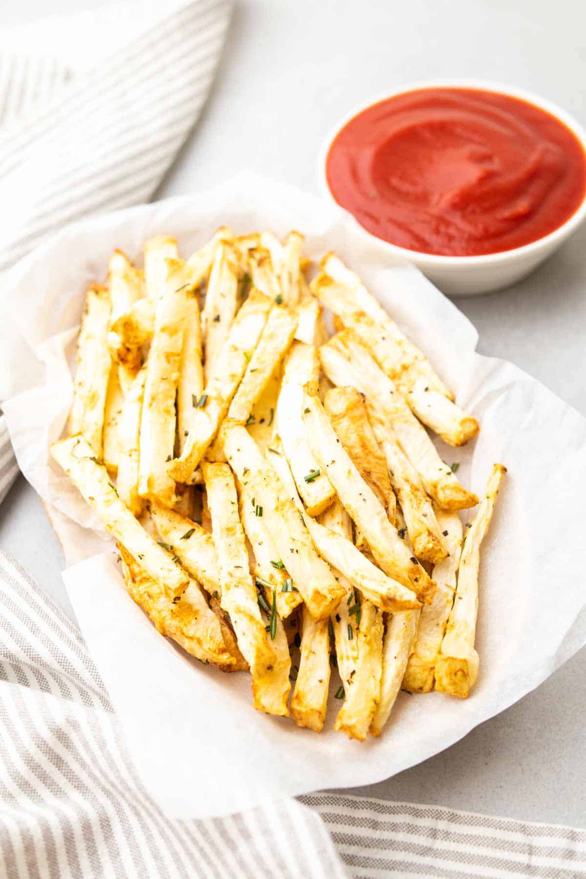 Gros plan de frites de céleri-rave dans un panier à côté d'un ramequin de ketchup