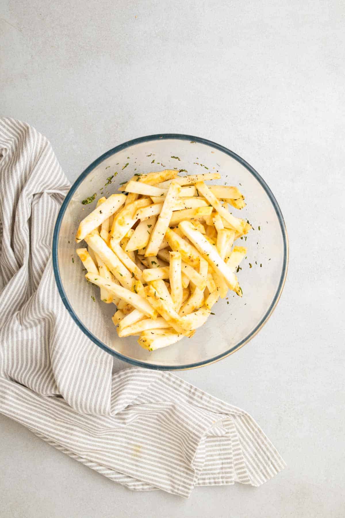 Frites mélangées à l'huile et au romarin dans un bol en verre, vues d'en haut