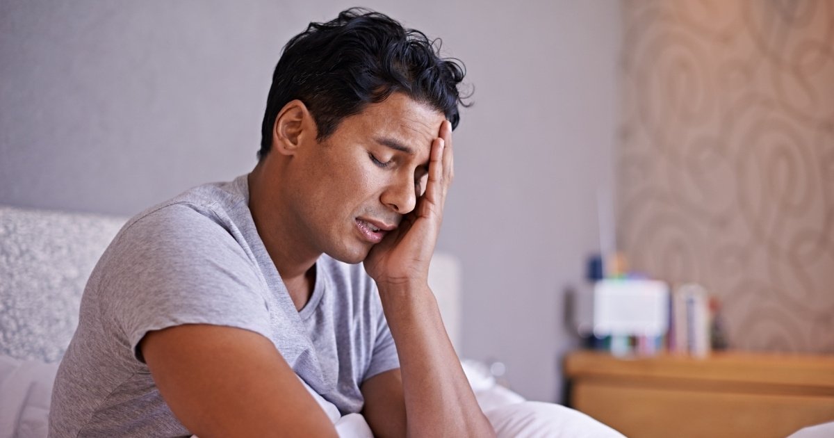 Homme assis dans son lit à la fatigue