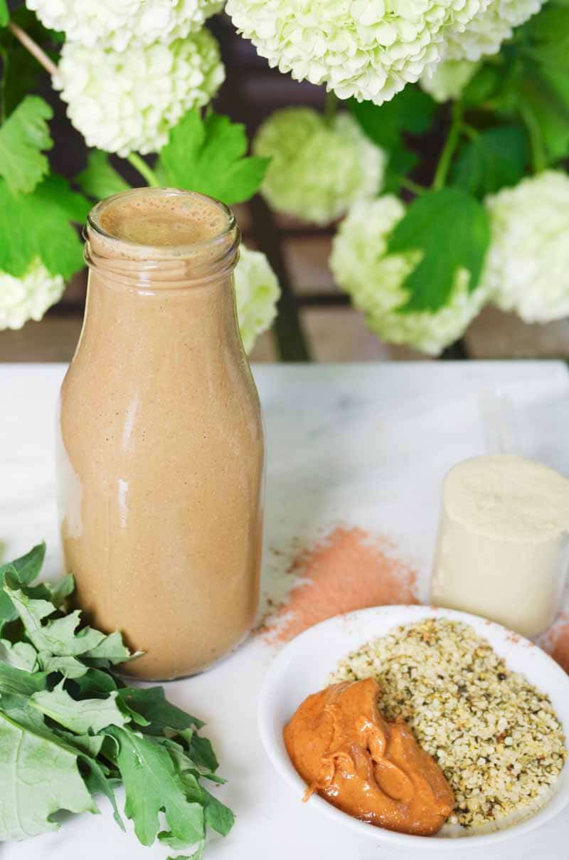 Bouteille de smoothie protéiné végétalien au beurre d'arachide entouré de tous les ingrédients bruts 