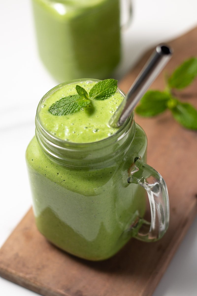 Smoothie céto vert dans un verre avec une paille et garni de menthe