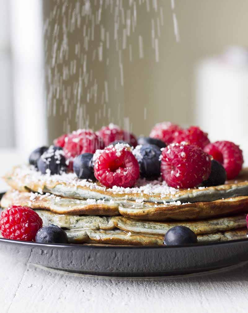 Saupoudrer de stévia sur une pile de crêpes avec des baies et du sirop sans sucre sur le dessus